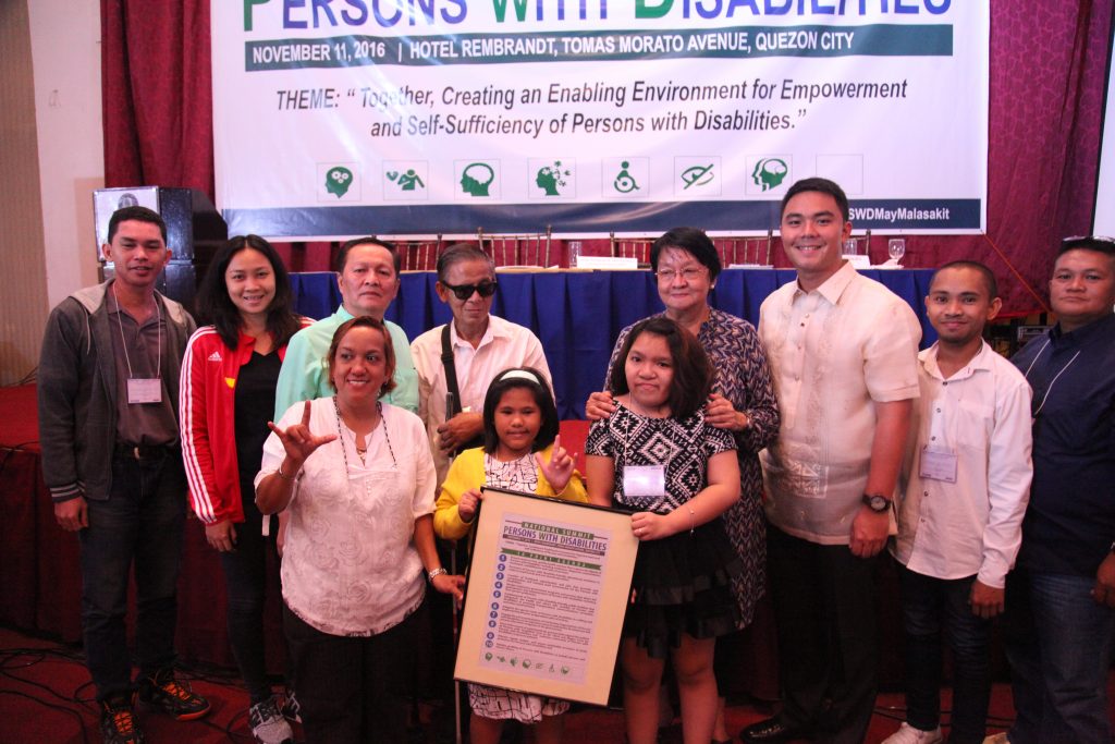 DSWD Secretary Judy Taguiwalo (4th from right) and Assistant Secretary Anton Hernandez (3rd from right)  beam as they pose with some PWD-participants of the national summit during the symbolic turn over of the PWD 10-Point Development Agenda.